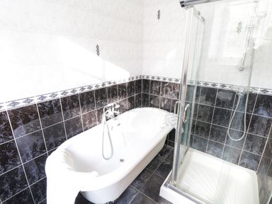 A bathroom with a bathtub and a glass door shower enclosure at The Old School House in Gortermone near Carrigallen County Leitrim