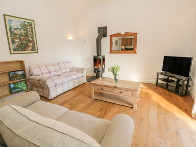 A living room with sofas a coffee table and a wood stove at Hen Stabl in Llangoed near Beaumaris