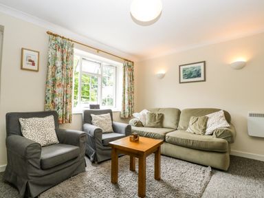 A living room with two armchairs a sofa and a wooden table at Wye Valley Cottage in Symonds Yat