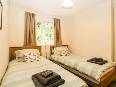 A bedroom with two single beds with animal print pillows and folded towels at Wye Valley Cottage in Symonds Yat