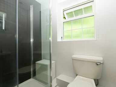 A bathroom with a toilet a glass shower enclosure and a window at Wye Valley Cottage in Symonds Yat