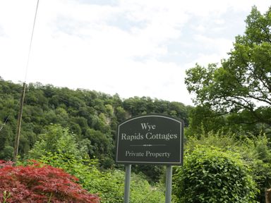 A sign that reads Wye Rapids Cottages Private Property surrounded by trees and bushes at Wye Valley Cottage in Symonds Yat