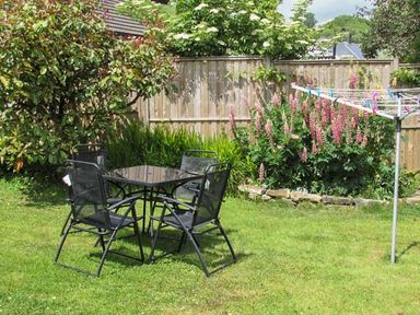 A garden with a black metal table and four chairs next to flowering plants and a rotary clothesline at Gorrig Bwthyn in Llandysul