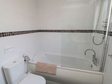 A bathroom with a toilet bidet and bathtub with shower at Orchard Lodge in Warkworth