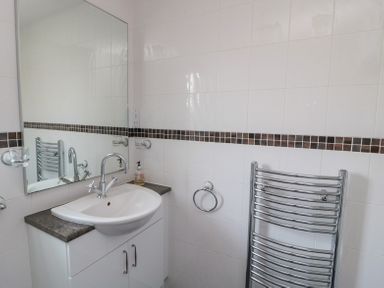 A bathroom sink with a mirror above and a towel rail on the wall at Orchard Lodge in Warkworth