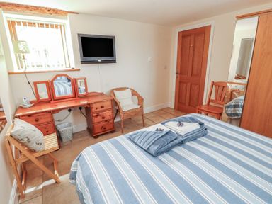 A bedroom with a bed and a dressing table at Piggery Cottage in Wigton