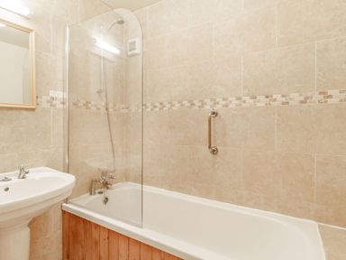 A bathroom with a bathtub shower combination and a sink at Horseshoe in Little Glemham near Wickham Market