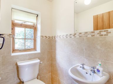 A bathroom with a toilet under a window and a sink with hand soap at Horseshoe in Little Glemham near Wickham Market