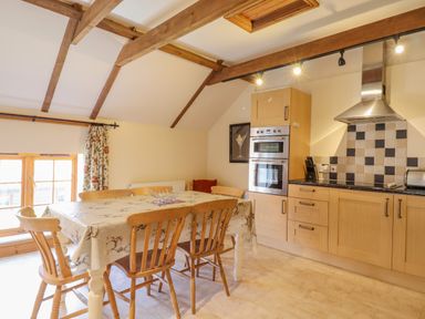 A kitchen with wooden dining table and chairs and modern appliances at Hayloft Cottage in Little Glemham near Wickham Market