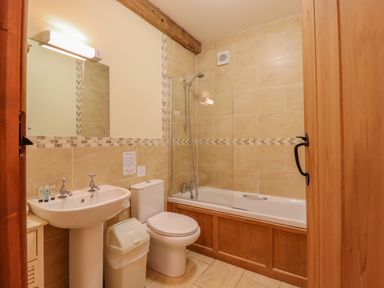 A bathroom with a sink toilet bathtub and mirror at Hayloft Cottage in Little Glemham near Wickham Market