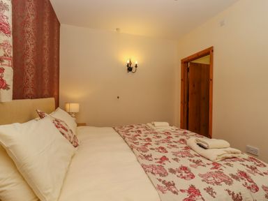 A bedroom with a double bed with patterned bedding and towels on top at Hayloft Cottage in Little Glemham near Wickham Market