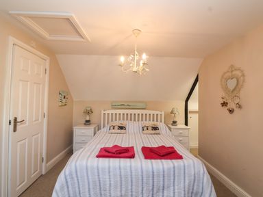 A bedroom with a double bed two bedside tables with lamps and towels on the bed at Enfield in Porlock