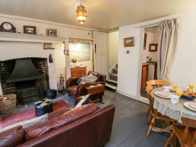 A living room with leather chairs a fireplace and a dining table set for breakfast at Inglenook Cottage in Whitby
