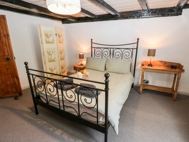 A bedroom with a metal bed frame side tables lamps and a wooden door at Inglenook Cottage Whitby