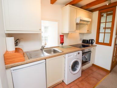 A kitchen with a sink a washing machine an oven and cabinets at The Bothy in Lowick near Holy Island