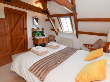 A bedroom with wooden beams a bed with towels and pillows and a wooden cabinet at The Bothy in Lowick near Holy Island