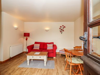 A living room with a red sofa table and chairs at Poppy Cottage in Little Glemham near Wickham Market