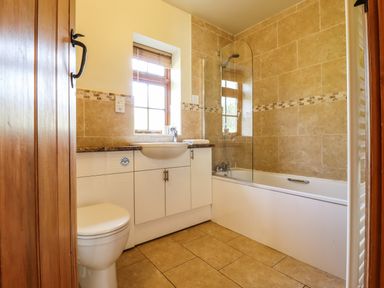 A bathroom with a toilet sink bathtub shower and wooden cabinet at Poppy Cottage in Little Glemham near Wickham Market