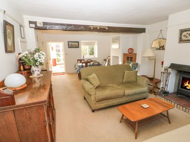 A living room with a green sofa wooden coffee table fireplace and dining area at 28 Oxborough in Oxborough