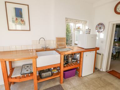 A kitchen corner with a wooden countertop sink and small white fridge at 28 Oxborough in Oxborough
