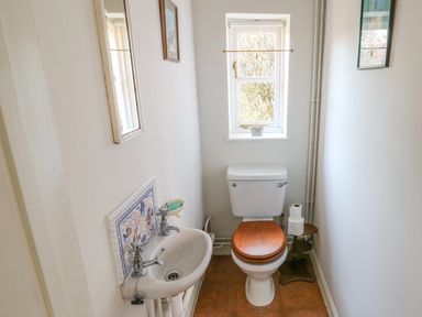 A small bathroom with a sink and toilet under a window at 28 Oxborough in Oxborough