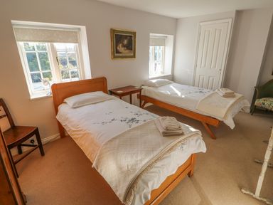 A bedroom with two single beds and a wooden chair at 28 Oxborough in Oxborough