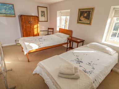 A bedroom with two single beds with white bedding and wooden furniture at 28 Oxborough in Oxborough