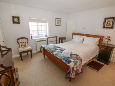 A bedroom with a wooden bed with white bedding and a colorful quilt at 28 Oxborough in Oxborough