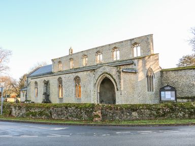 A stone church building with arched windows and a moss-covered wall in front at 28 Oxborough in Oxborough
