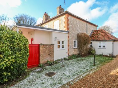 A stone and brick house with a red gate and gravel path at 28 Oxborough in Oxborough