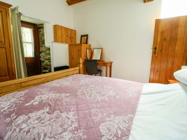 A bedroom with a bed and dresser at Bythyn Ddol Hafod in Capel Curig
