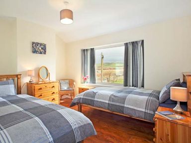 A bedroom with two single beds and wooden furniture near a window at Trysor Y Mor in Borth