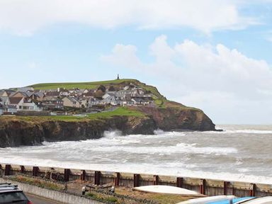 A coastal village with houses on a cliff and rough sea waves at Trysor Y Mor in Borth
