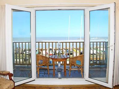 A balcony with two chairs and a table overlooking the sea at Trysor Y Mor in Borth