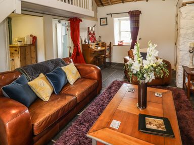 A living room with leather sofas wooden coffee table with flowers and a desk at New Thatch Farm in Scarteen near Knocklong County Limerick