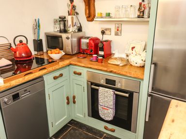 A kitchen corner with mint green cabinets wooden countertop a red kettle microwave toaster and coffee machine at New Thatch Farm Scarteen near Knocklong County Limerick