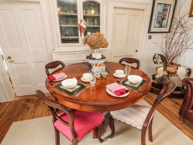 A dining room with a round wooden table set with bowls and glasses and wooden chairs at New Thatch Farm Scarteen near Knocklong County Limerick