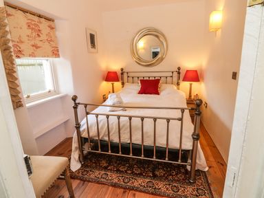 A bedroom with a metal bed frame a rug two bedside lamps and a window at New Thatch Farm in Scarteen near Knocklong County Limerick