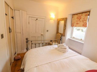 A bedroom with a metal bed frame folded towels on the bed a chair a mirror on the wall and a window with a patterned blind at New Thatch Farm Scarteen near Knocklong County Limerick