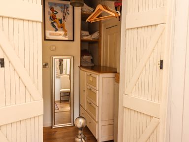 A closet with white wooden doors a mirror a dresser wooden hangers and folded towels at New Thatch Farm in Scarteen near Knocklong County Limerick
