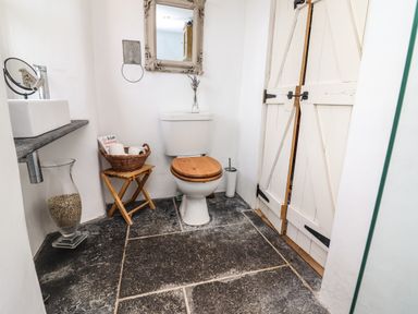 A bathroom with a toilet wooden seat a basket with toilet paper a sink and a mirror at New Thatch Farm Scarteen near Knocklong County Limerick