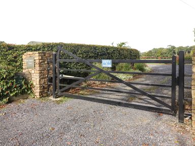 A black metal farm gate with a cctv sign on a gravel driveway at New Thatch Farm Scarteen near Knocklong County Limerick