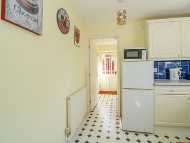 A kitchen with a refrigerator microwave cabinets and tiled floor at The Granary Cottage in Gayton near King's Lynn