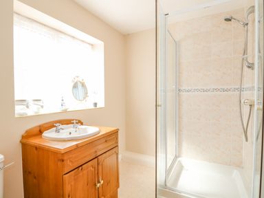 A bathroom with a wooden cabinet sink and a glass shower enclosure at The Granary Cottage in Gayton near Kings Lynn