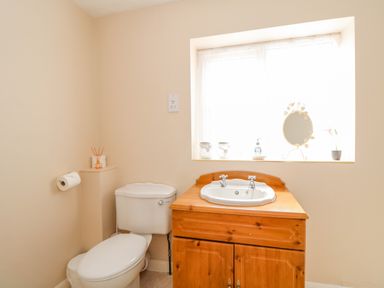 A bathroom with a toilet a wooden vanity with a sink and a window above at The Granary Cottage in Gayton near Kings Lynn