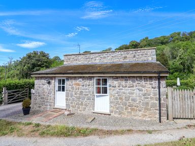 A stone building with double doors and a gravel path at The Lambing Shed in Dyserth near Prestatyn
