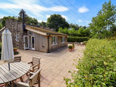 An outdoor area with a house, table, chairs, and plants at The Lambing Shed Dyserth near Prestatyn