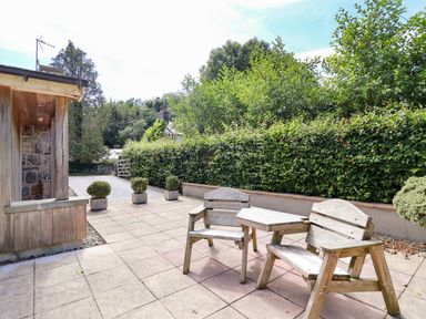 A garden with wooden chairs and a table at The Lambing Shed Dyserth near Prestatyn