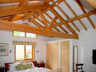 A bedroom with exposed wooden beams above a bed with green pillows and wooden furniture at The Springs in Ashey near Brading and Ryde