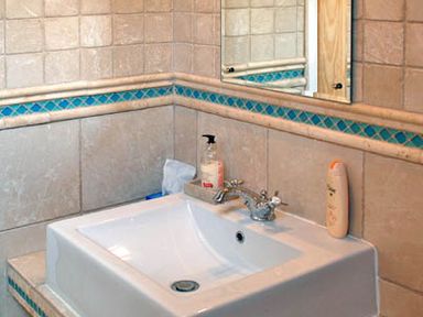 A bathroom sink with a faucet soap dispenser and lotion bottle with tiled walls at The Springs in Ashey near Brading and Ryde
